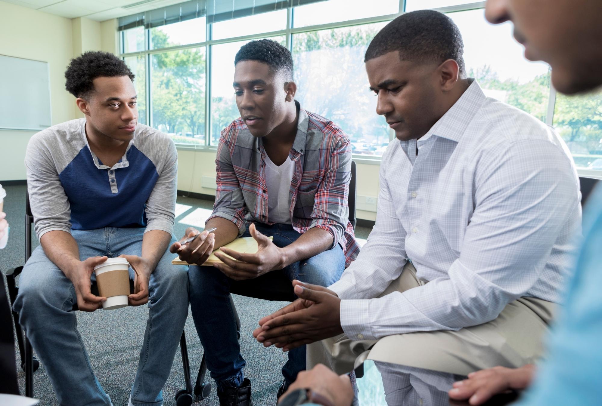 Black men sitting in a group mental health therapy session