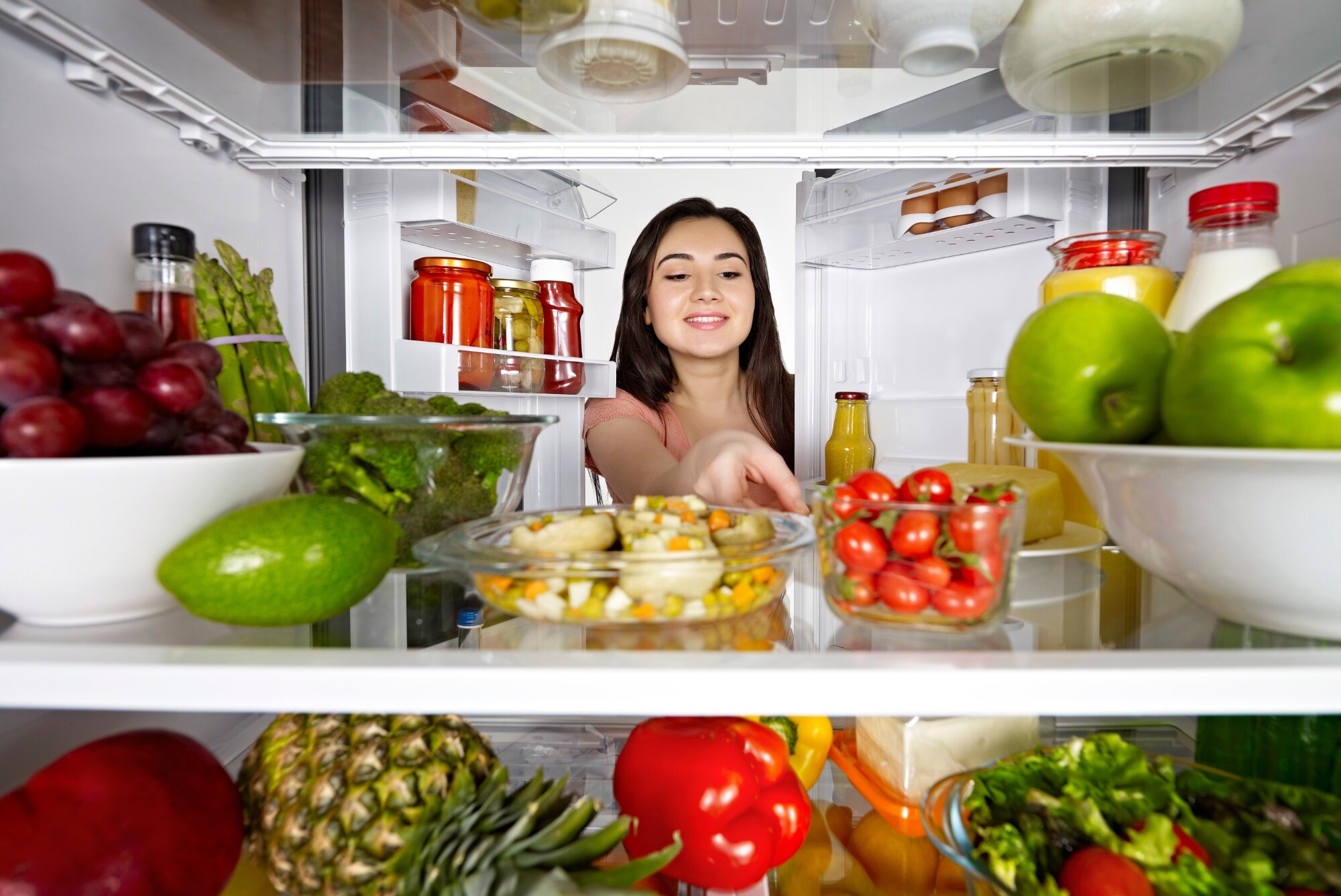 Woman reaching into the refrigerator to select a healthy meal.