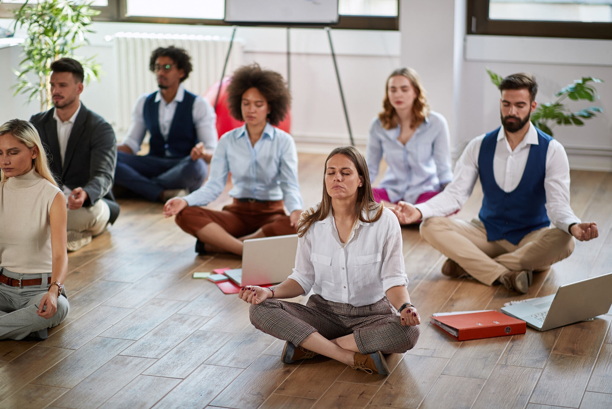 Professional colleagues sitting on the floor meditating as a group.