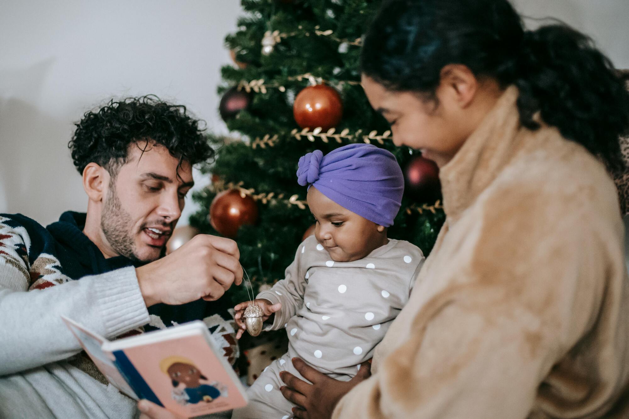 Family sitting in front of the christmas tree celebrating the holiday season